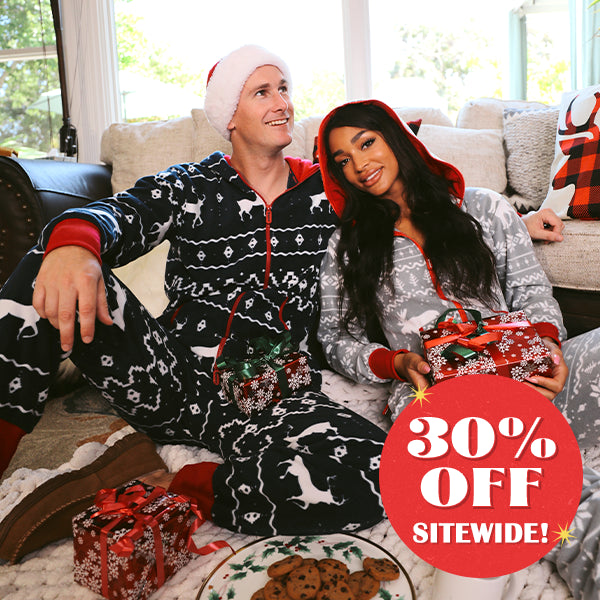 Shop christmas onesies - model wearing men's blue reindeer jumpsuit and women's grey moose jumpsuit